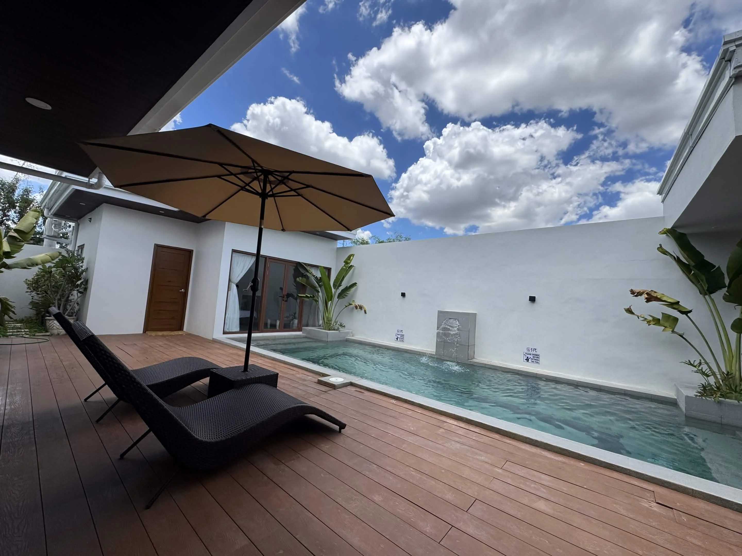 Private pool with sun loungers, umbrella and tropical landscaping