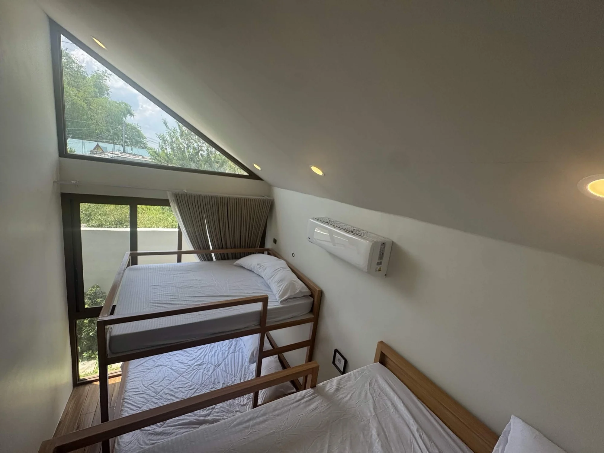 Second bedroom with queen-over-queen bunk beds, dramatic angled skylight window and air-conditioning